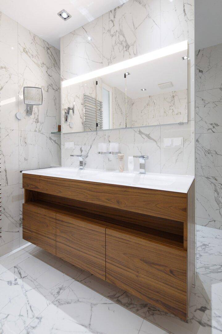 Modernes Badezimmer mit Doppelwaschbecken, Holzunterschrank und großem Spiegel.