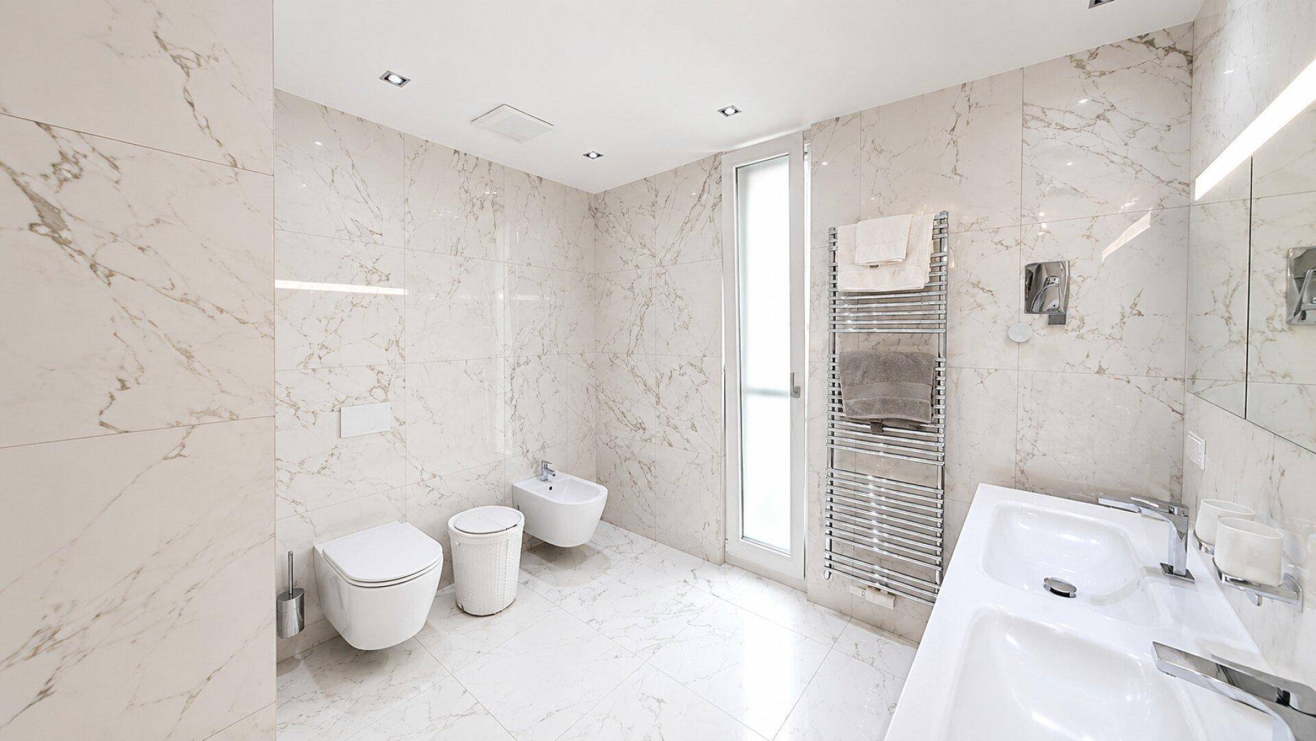 Luxuriöses Badezimmer mit Marmorfliesen, Doppelwaschbecken und Bidet.