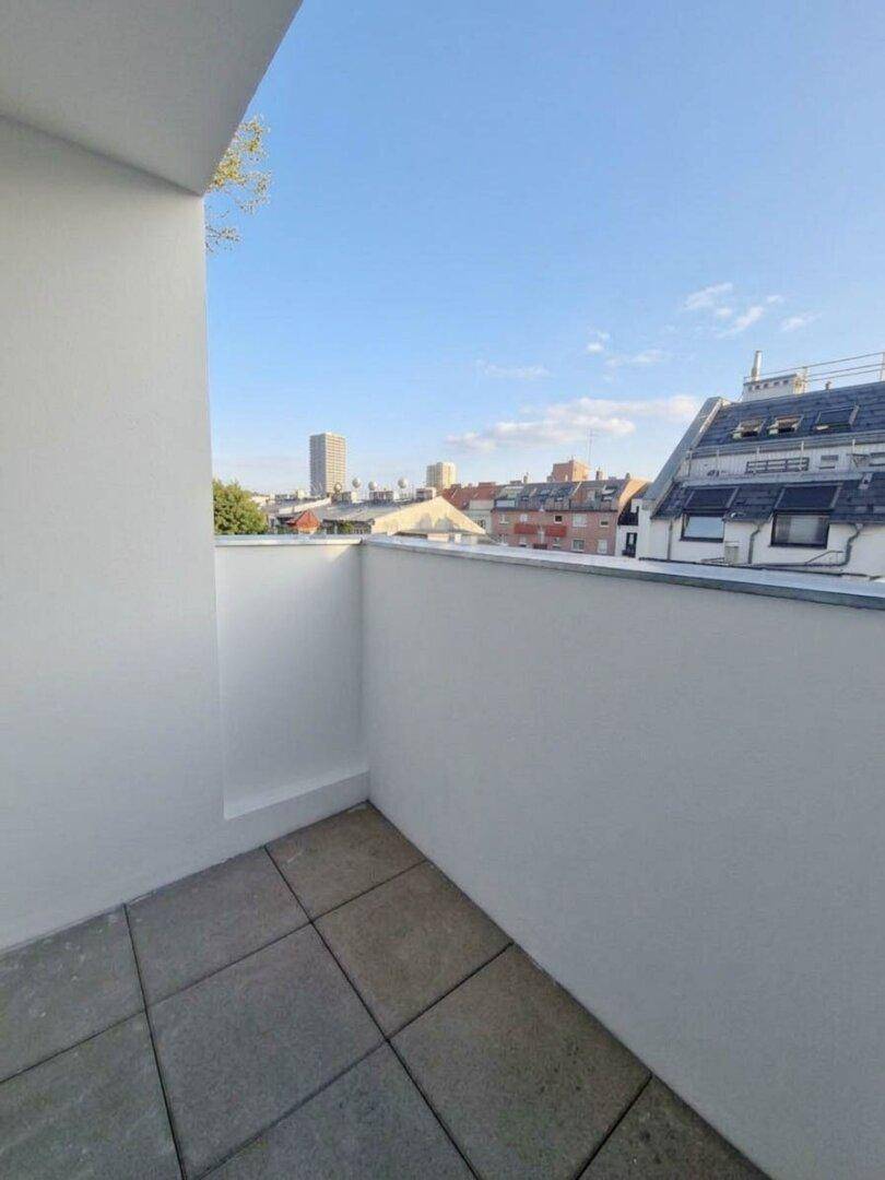 Heller Balkon mit Stadtblick und gefliestem Boden, ideal für entspannte Stunden.
