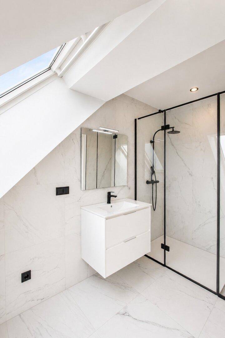Elegantes Badezimmer mit begehbarer Dusche, Marmorfliesen und einem hellen Dachfenster.