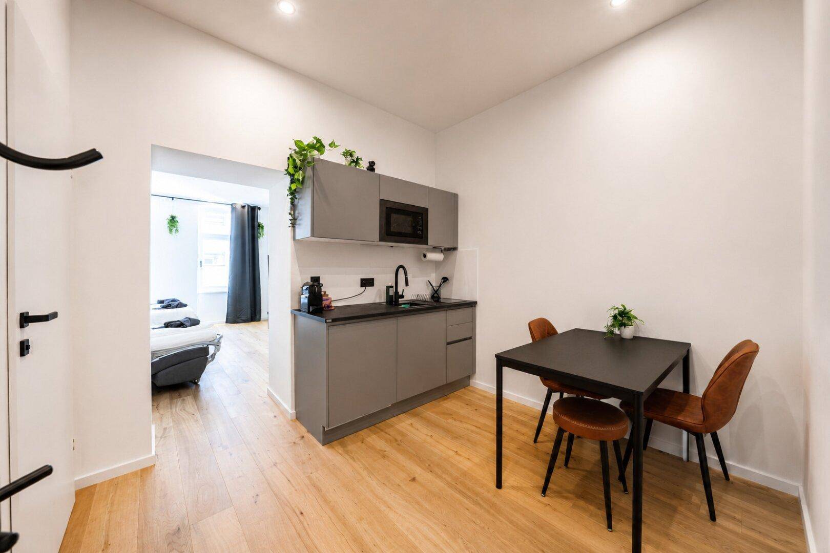Moderne Küchenzeile mit Essbereich und Blick in den angrenzenden Schlafbereich des Apartments.