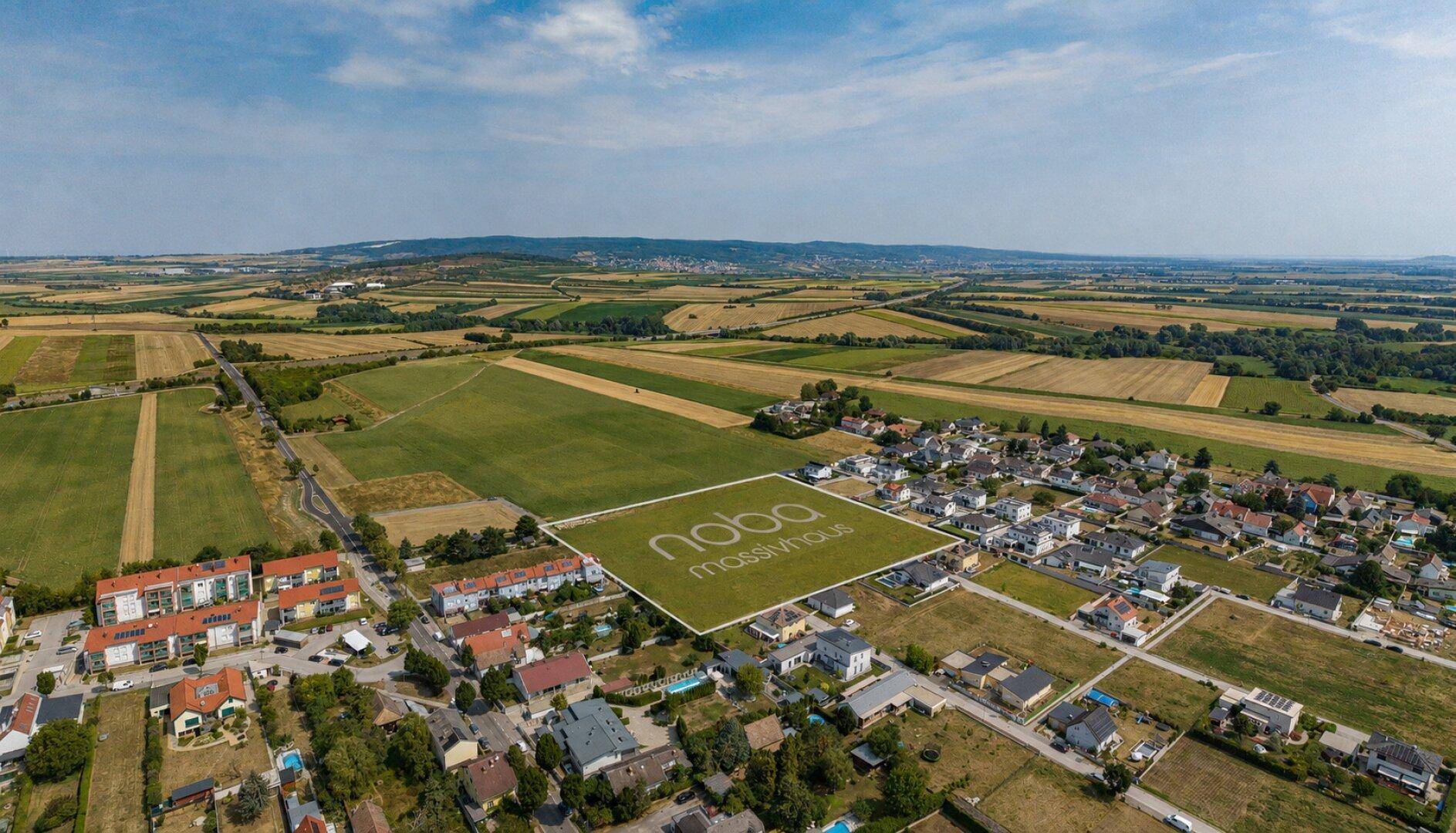Panoramablick aus der Luft auf ein Entwicklungsgelände in einer ruhigen Wohnsiedlung mit grüner Umgebung.