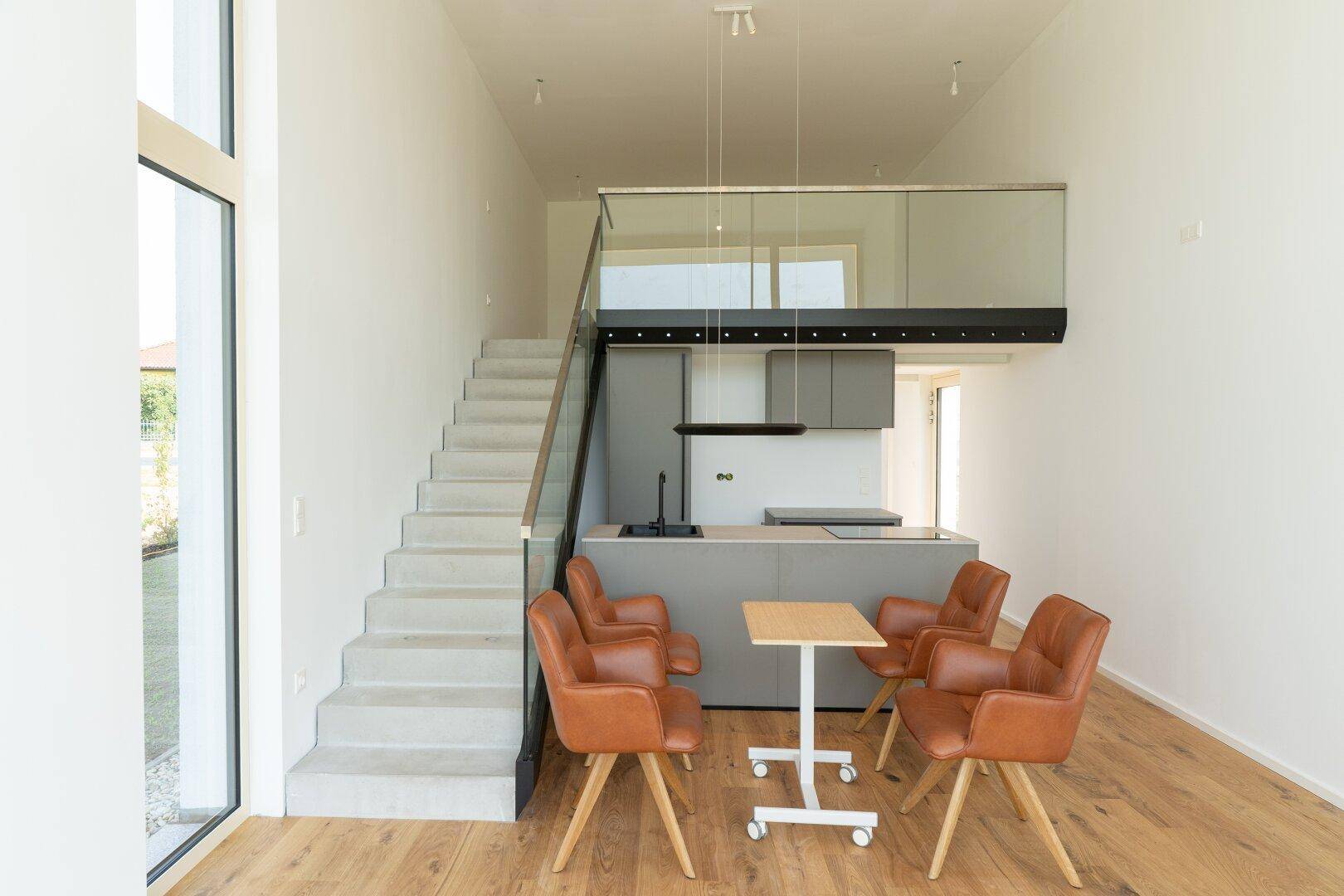 Heller offener Wohnbereich mit moderner Küche, Holzboden und Treppe zur Galerie.