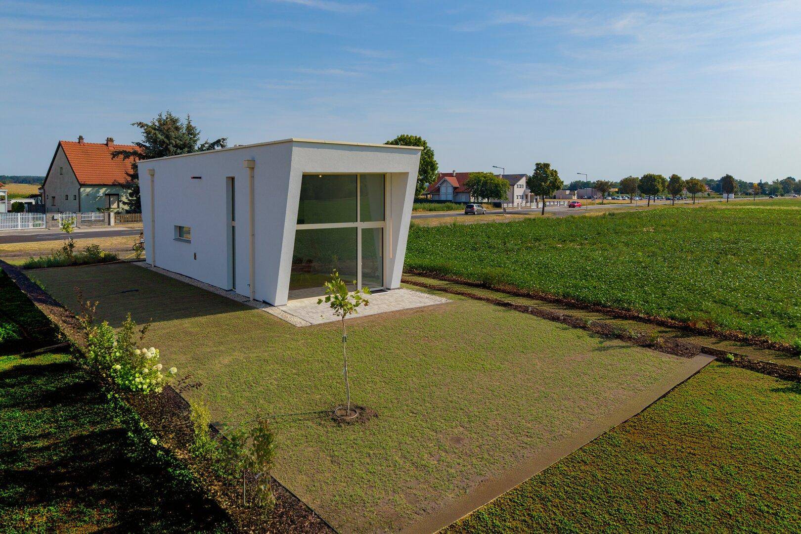 Modernes Einfamilienhaus mit großer Rasenfläche und weitem Blick auf die Landschaft.