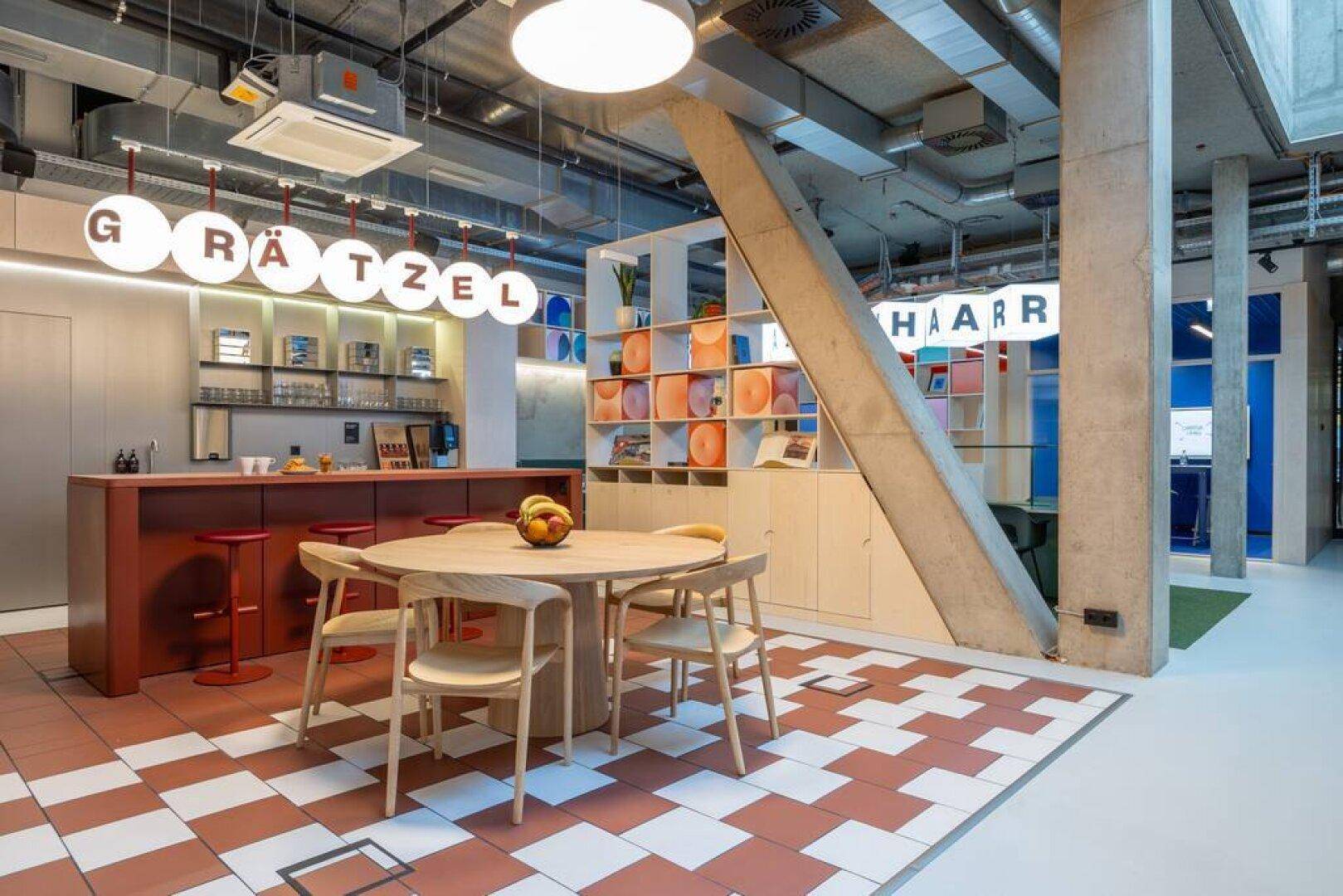 Offener Küchen- und Essbereich in einem Büro mit Holztisch, Stühlen und einer modernen Bar.
