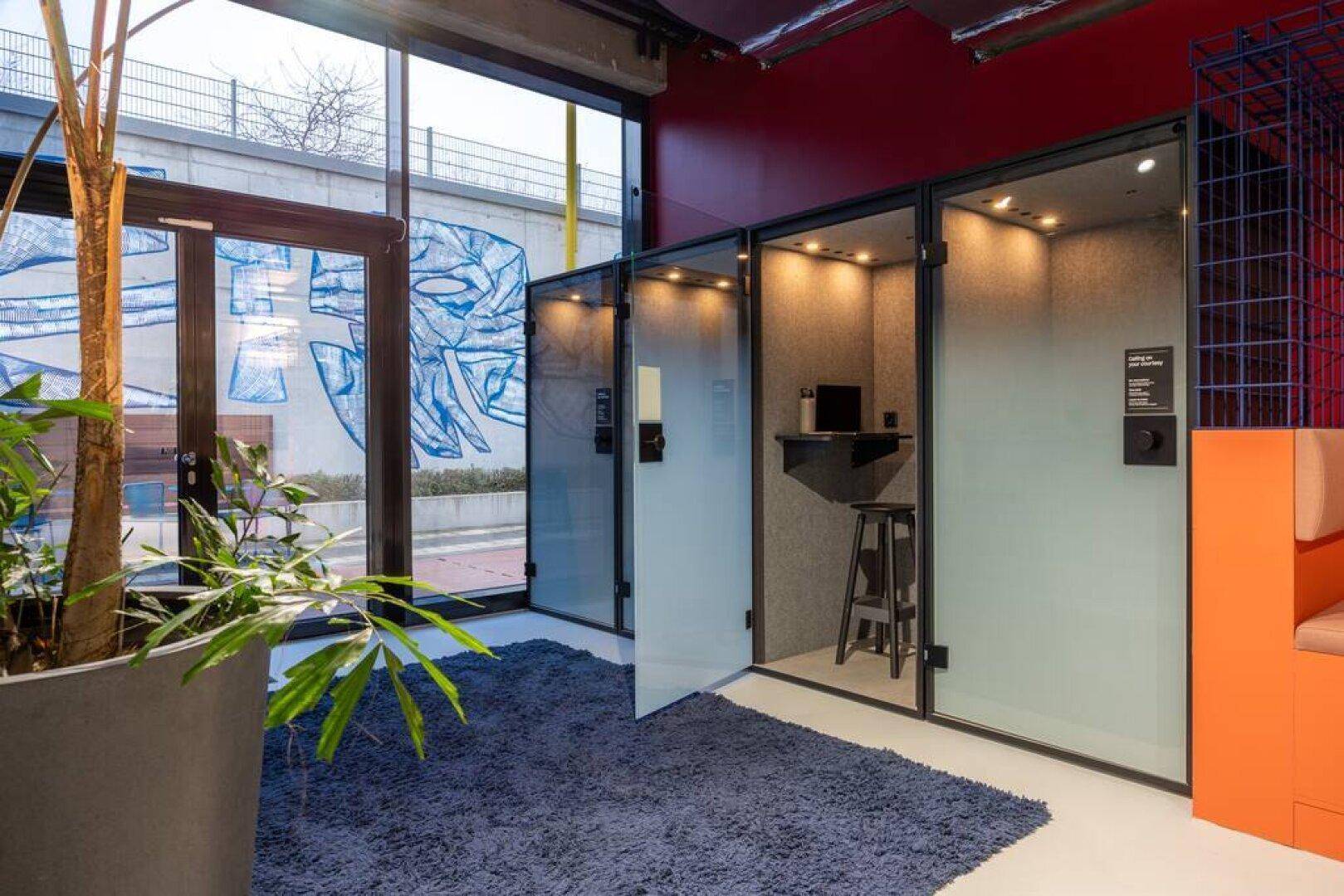 Moderne Einzelarbeitskabinen in einem Büro mit großen Fenstern, ideal für konzentriertes Arbeiten.