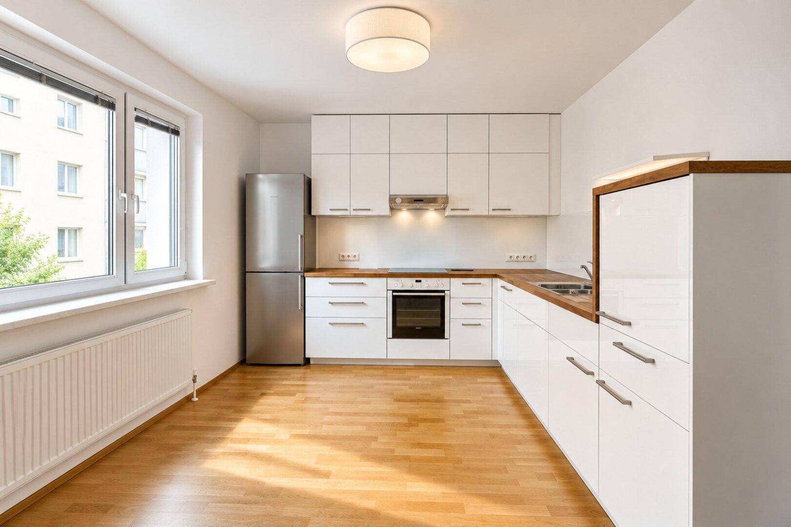 Moderne Einbauküche mit weißen Schränken, Holz-Arbeitsplatte und integrierten Geräten.