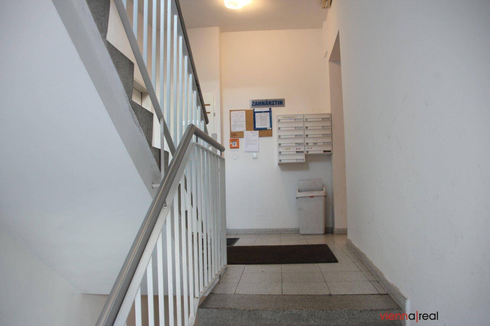 Treppenhaus im Eingangsbereich mit Briefkästen und Informationen, führt zu den oberen Etagen des Gebäudes.