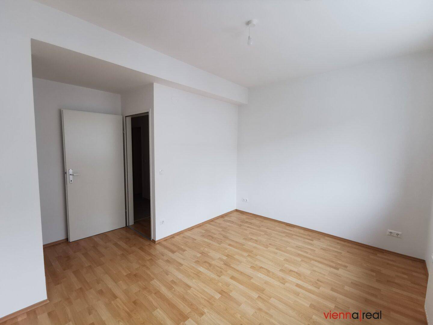 Helles Zimmer mit Parkettboden und weiß gestrichenen Wänden, bietet eine neutrale Basis für individuelle Einrichtung.