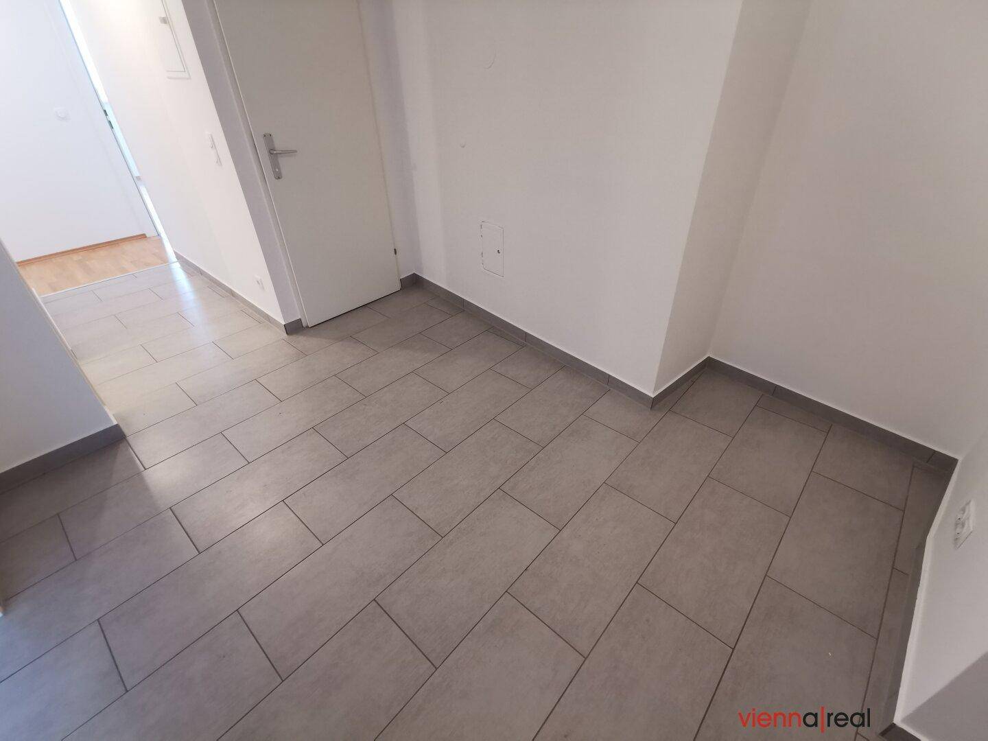 Geräumiger Flur mit modernen grauen Fliesen, bietet Zugang zu verschiedenen Bereichen der Wohnung.