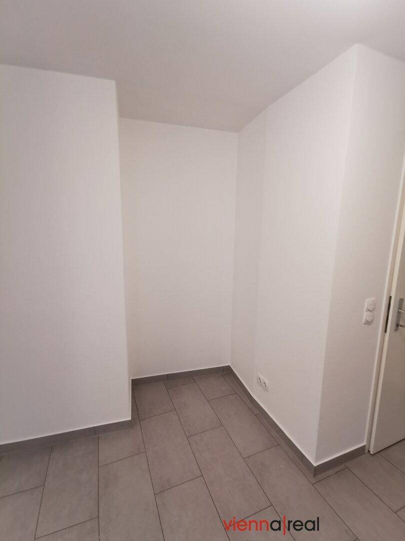 Kleiner Abstellraum mit grauen Fliesen und weißen Wänden, ideal für zusätzlichen Stauraum.