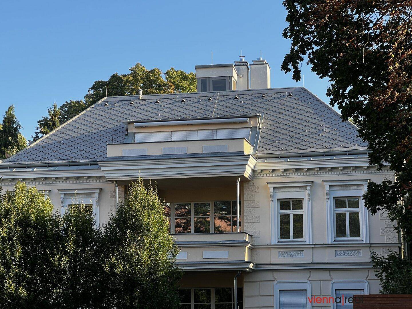 Elegante Gebäudefassade mit klassischer Architektur, Balkonen und einem markanten Dach.