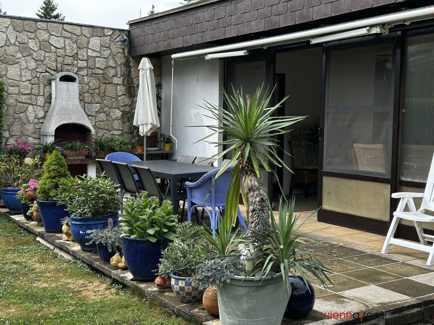 Gemütliche Terrasse mit Steingrill und vielen Pflanzen, ideal für gesellige Abende im Freien.