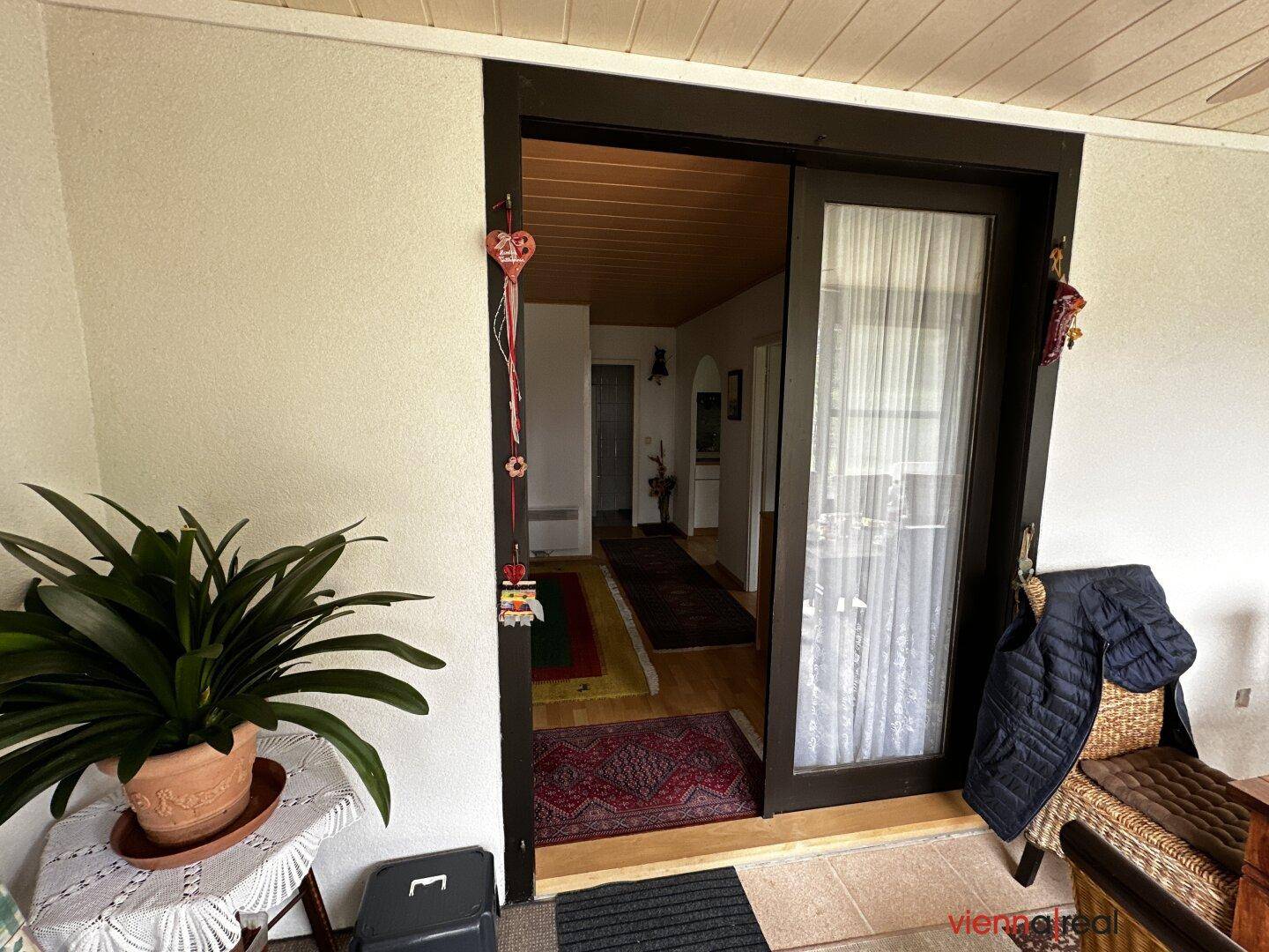 Eingangsbereich vom Wintergarten in den Flur mit Holzboden und Teppichen.