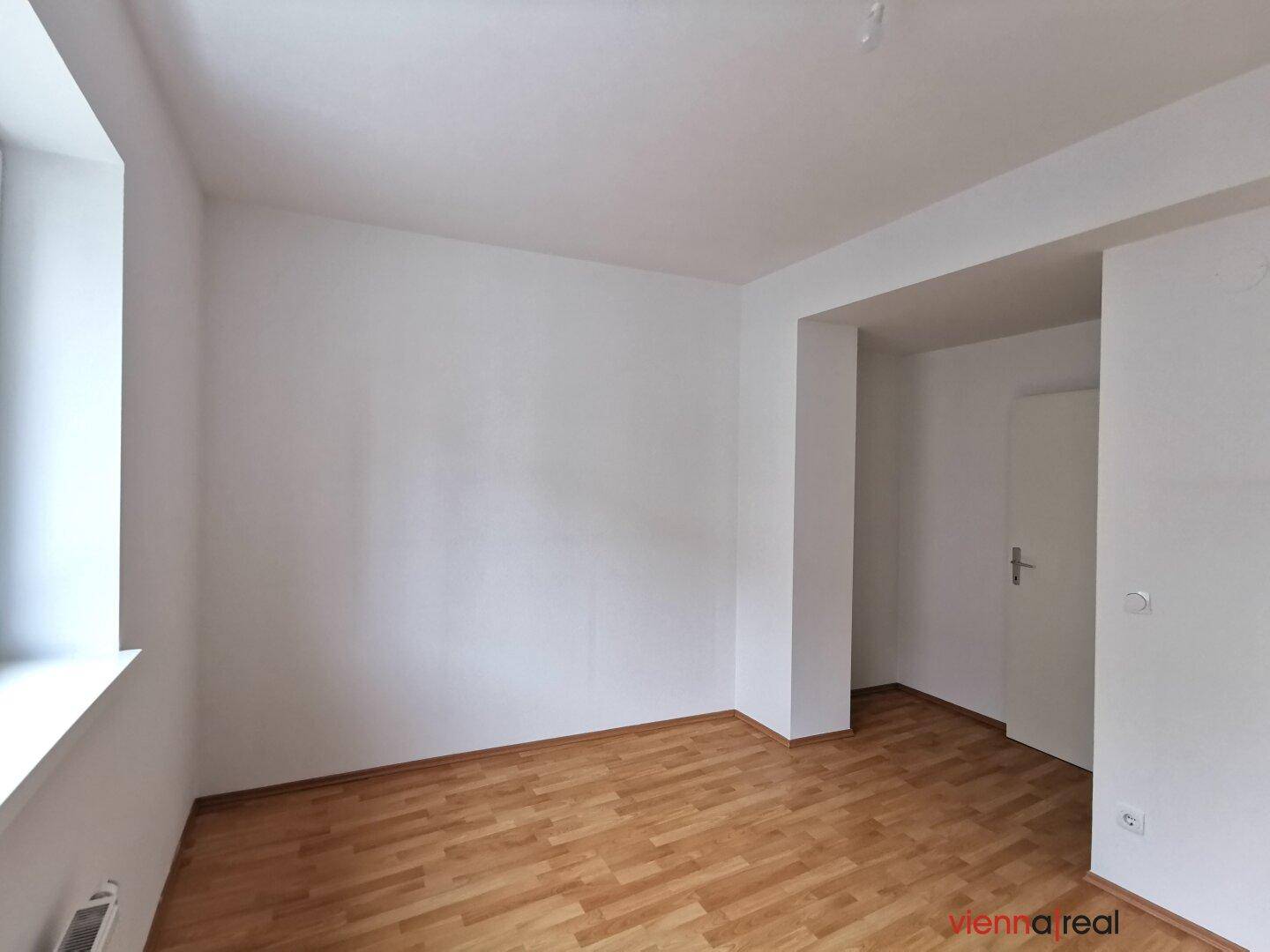 Heller Raum mit Holzboden und einer Nische, die zusätzlichen Platz bietet.