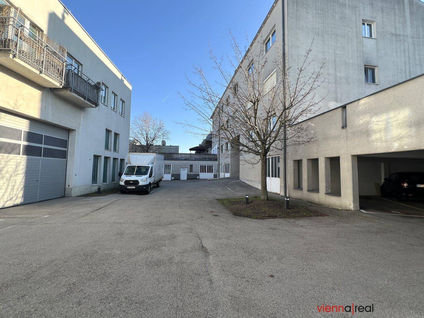Großer Außenbereich mit Parkplätzen und verschiedenen Gebäuden im Hintergrund unter klarem Himmel.