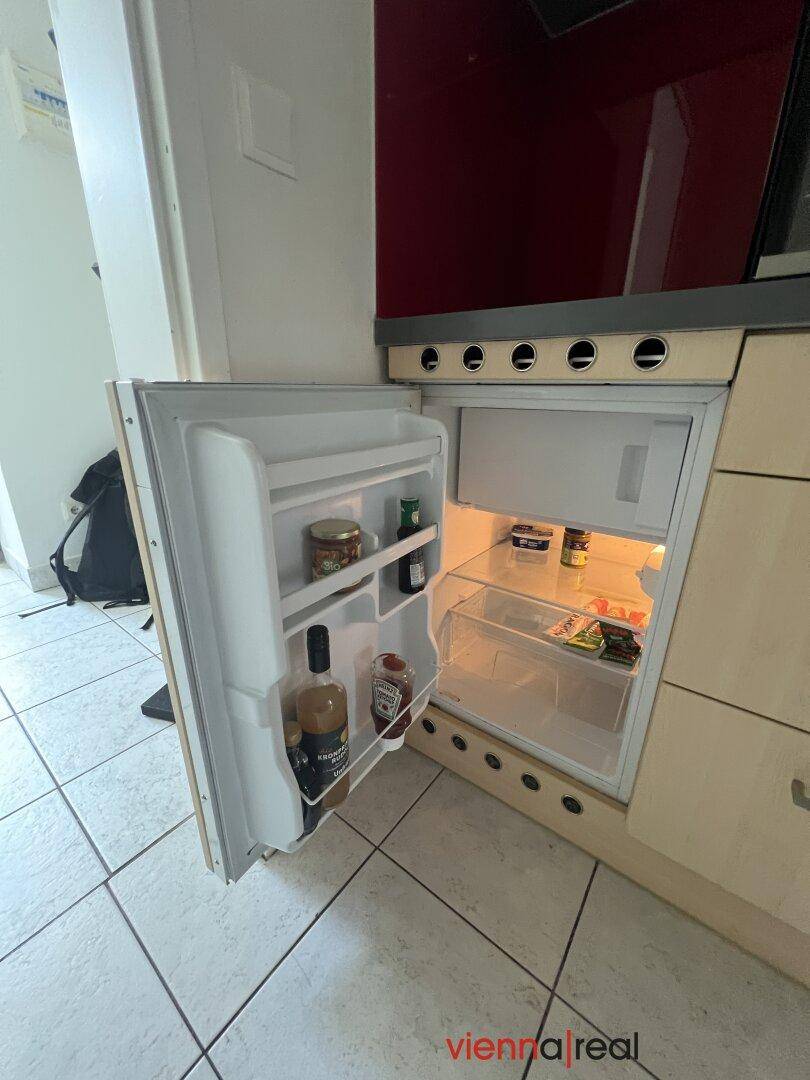 Kleiner Kühlschrank mit Gefrierfach, praktisch in die Küchenzeile integriert.