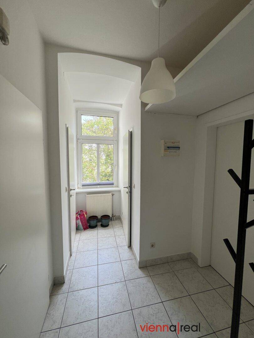 Heller Flur mit Fenster und Fliesenboden, der zu den verschiedenen Räumen führt.