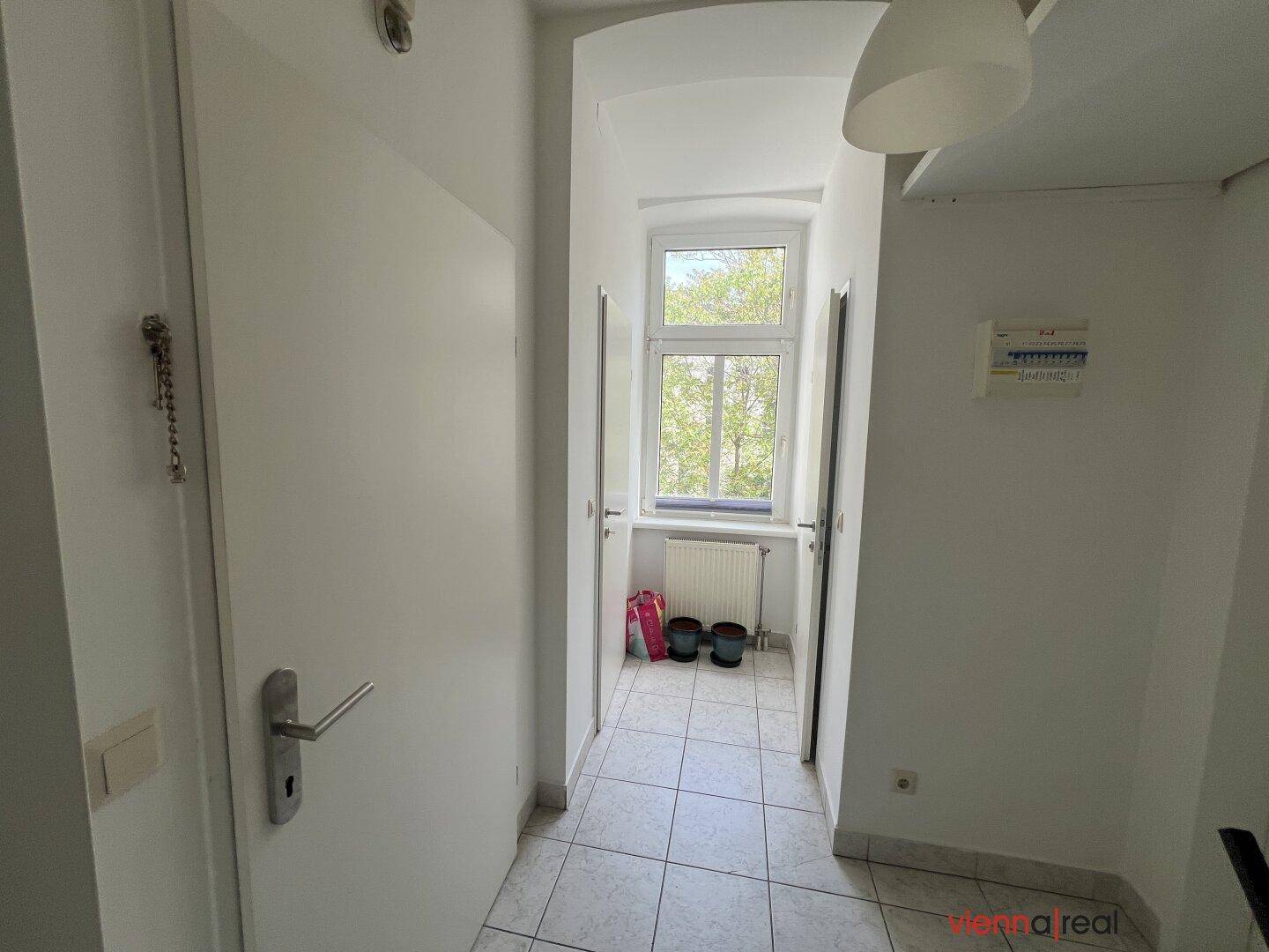 Heller Flur mit Fenster und Fliesenboden, der zu den verschiedenen Räumen führt.