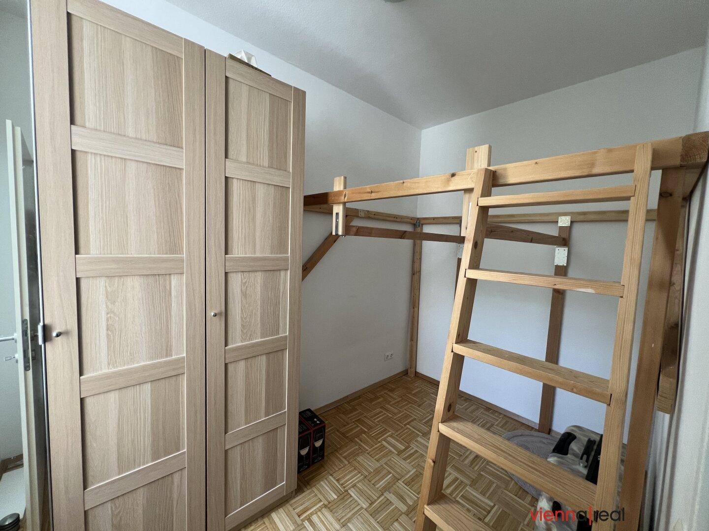 Schlafzimmer mit Hochbettkonstruktion aus Holz und einem großen Kleiderschrank.