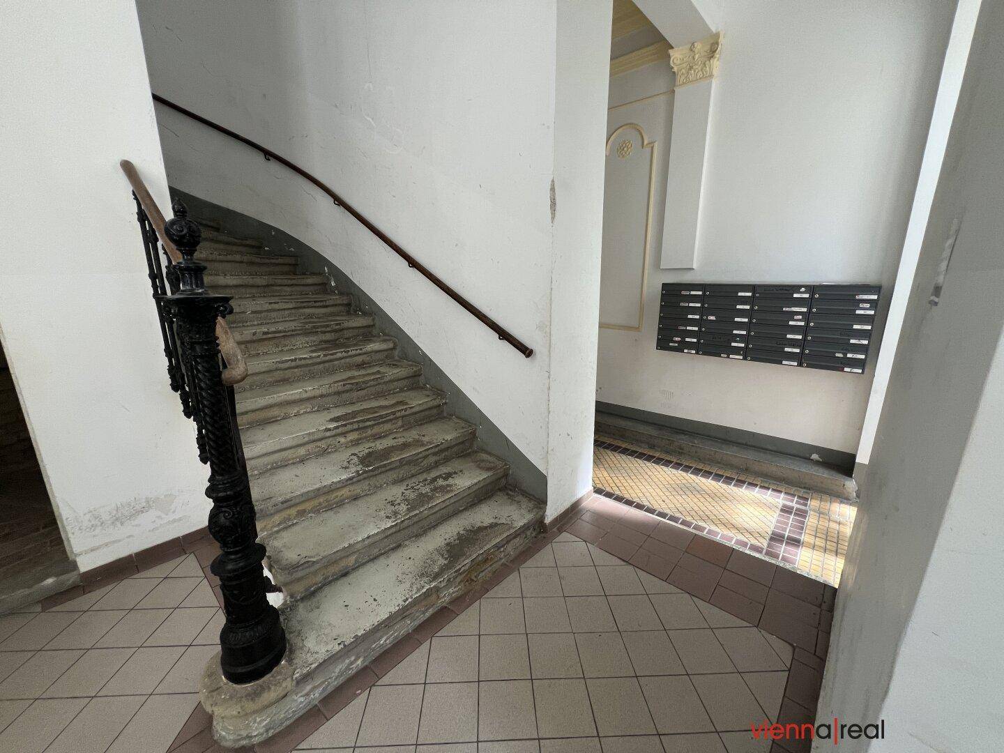 Historisches Treppenhaus mit geschwungener Treppe und traditionellem Geländer.