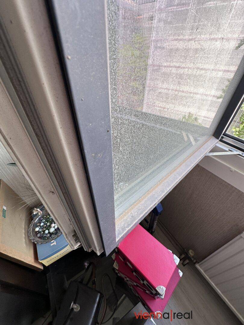 Blick von einem Fensterbrett nach unten, mit Sicht auf den Fensterrahmen und Baugerüste.