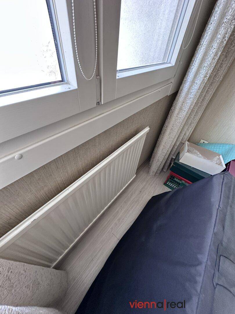 Detailansicht eines Fensters mit Heizkörper darunter und Vorhängen.