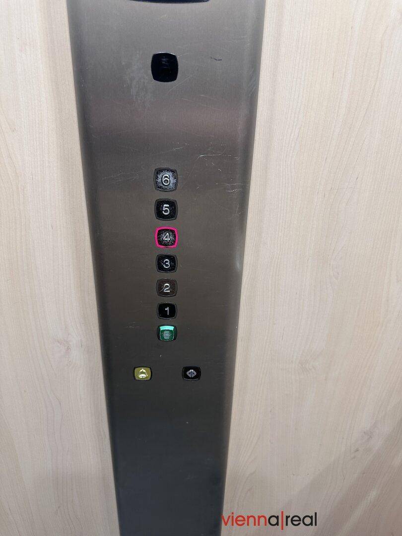 Aufzugbedienfeld mit beleuchteten Stockwerktasten und Notruffunktion.