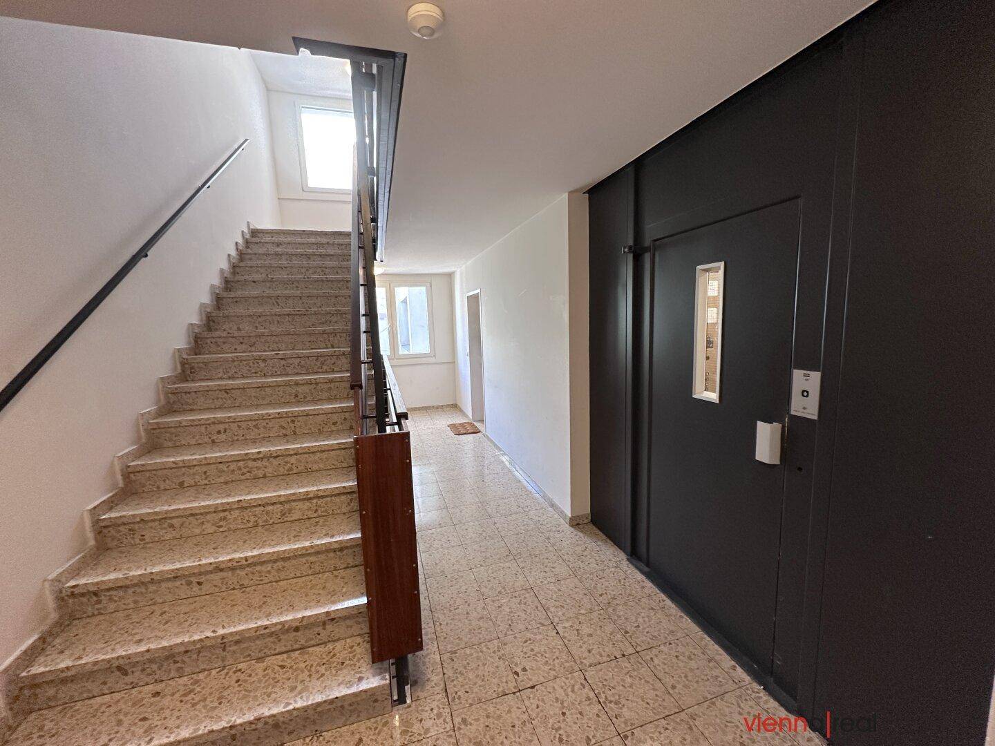 Treppenhaus und Aufzug in einem Mehrfamilienhaus, gut beleuchtet und gepflegt.