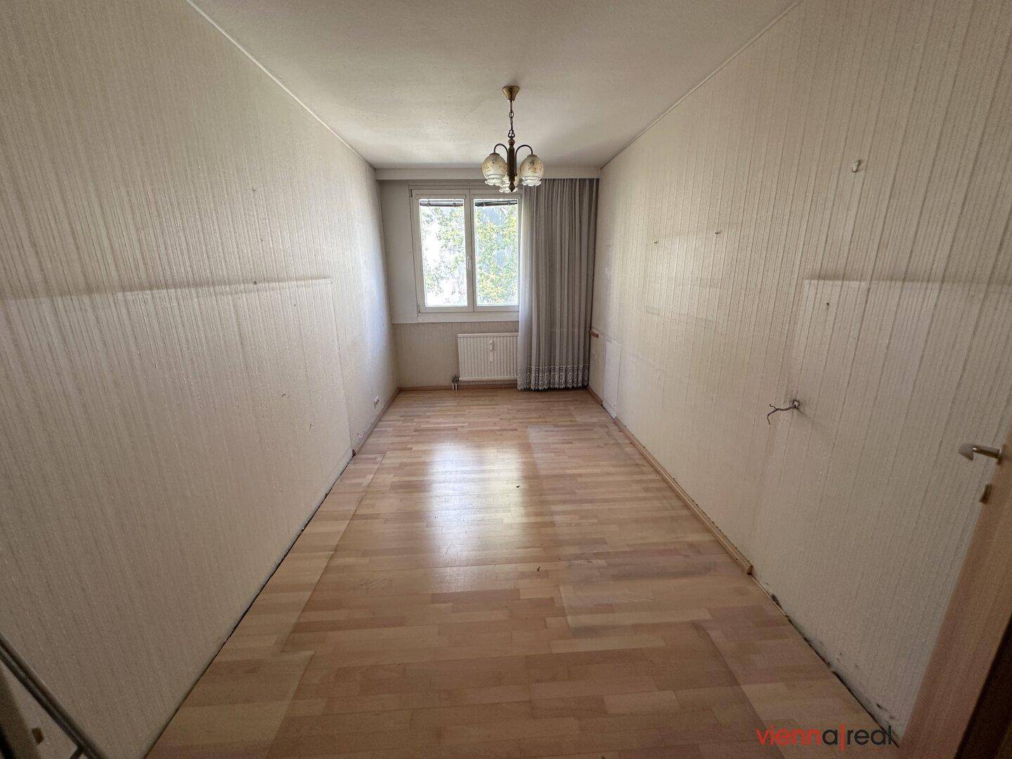 Leeres Zimmer mit hellem Holzboden und Fenster, bereit zur individuellen Gestaltung.