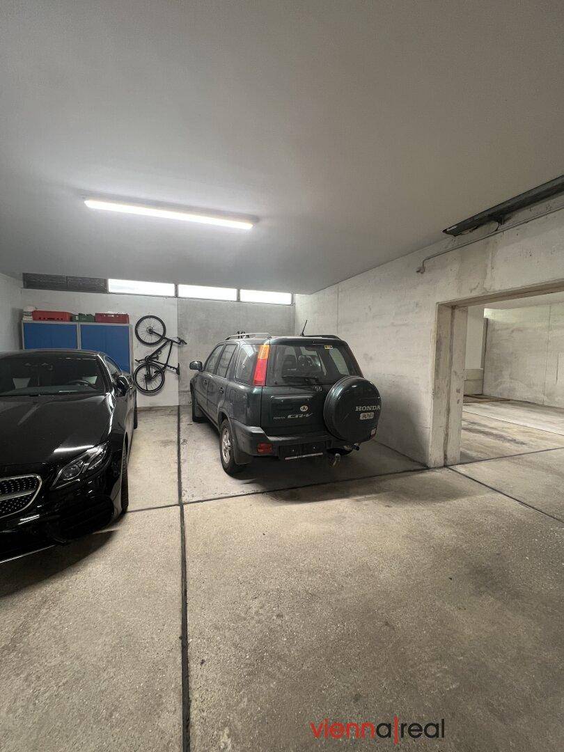 Tiefgarage mit zwei geparkten Autos und einem Fahrrad an der Wand.