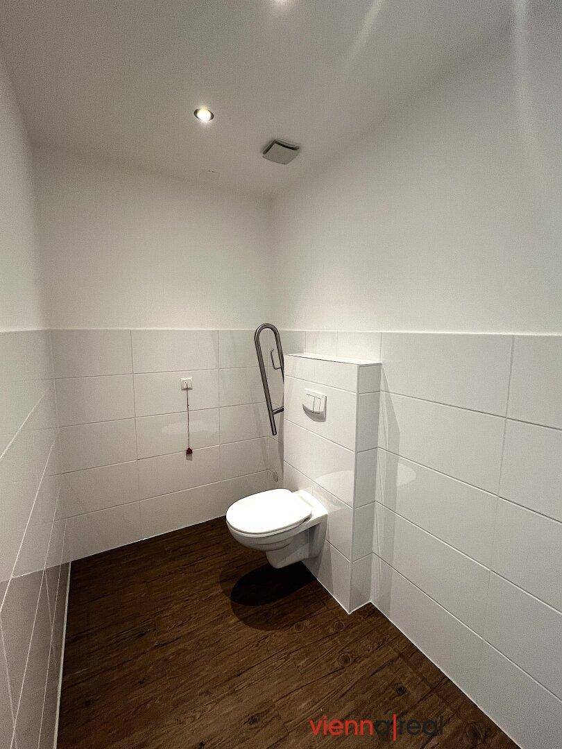 Barrierefreie Toilette mit Haltegriffen und wandhängendem WC, praktisch und zugänglich.