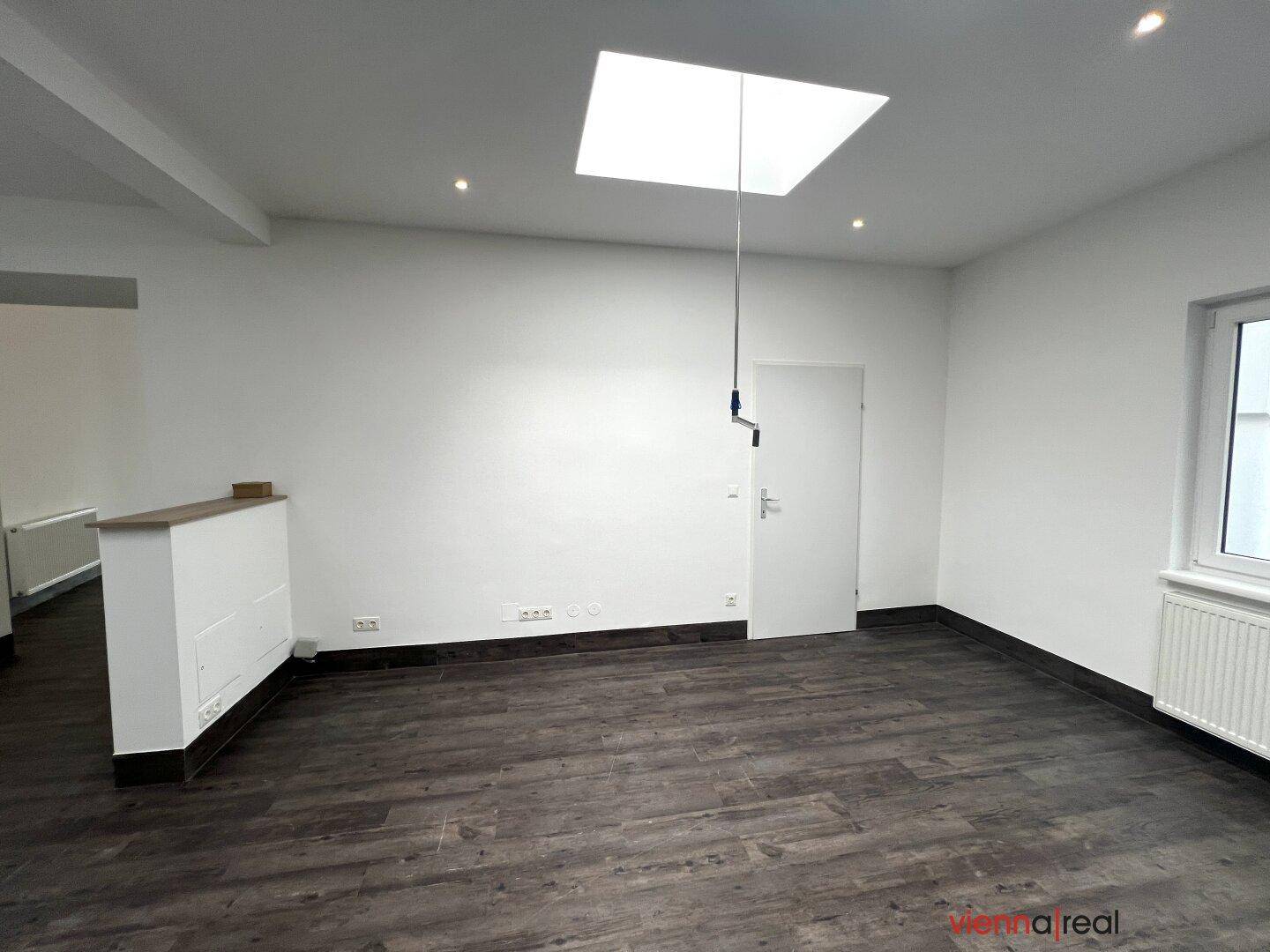 Ecke eines hellen Gewerberaums mit kleiner Theke, Fenster und einem Oberlicht, ideal für flexible Nutzung.