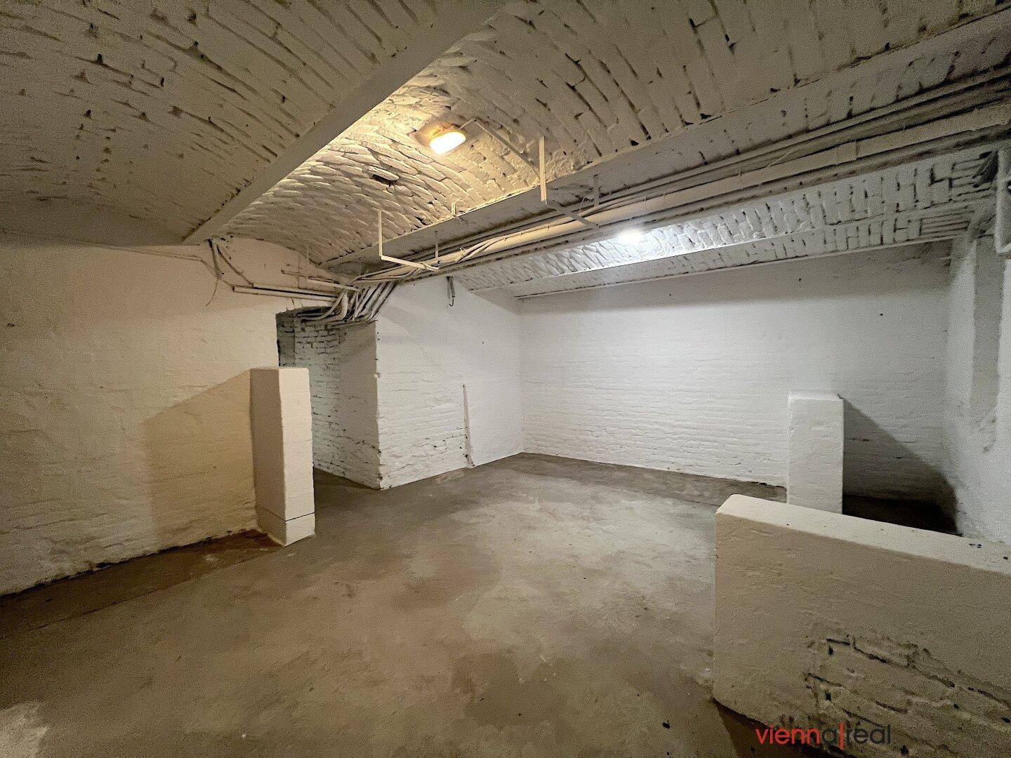 Kellerraum mit weiß gestrichener Ziegeldecke und Betonboden, bietet zusätzlichen Stauraum.