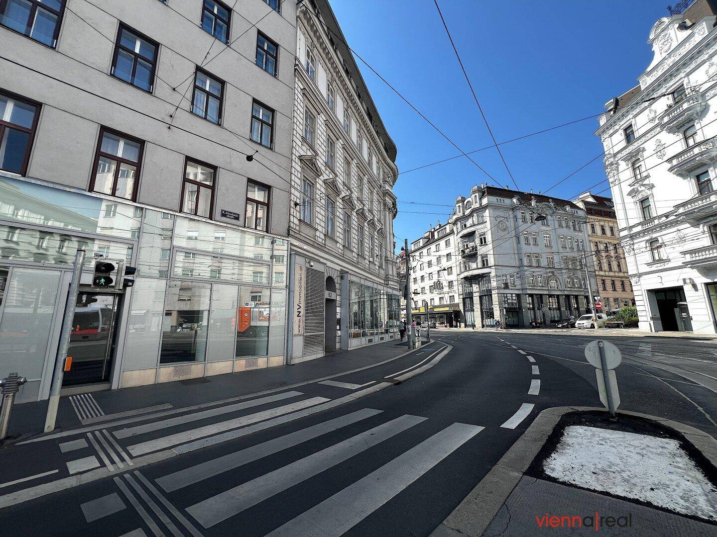 Weitläufige Straßenansicht mit Zebrastreifen und historischen Gebäuden unter blauem Himmel.