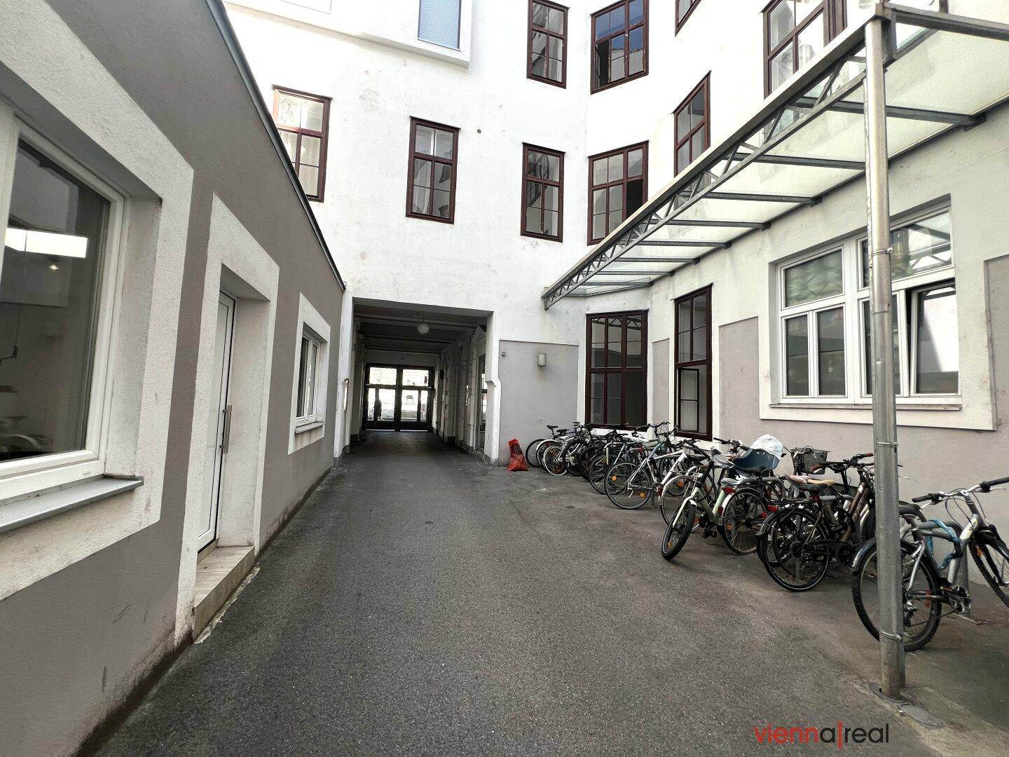 Innenhof mit überdachtem Fahrradabstellplatz und einem Durchgang zu weiteren Gebäudeteilen.