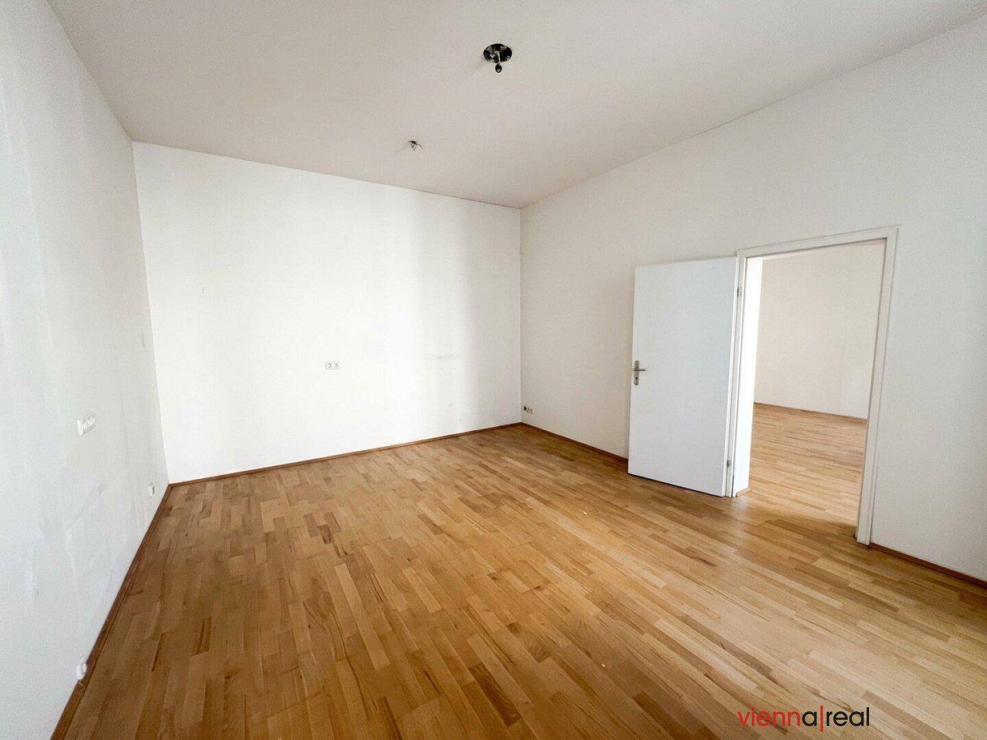 Unmöblierter Raum mit Parkettboden und weiß gestrichenen Wänden, ideal für Wohn- oder Schlafzimmer.
