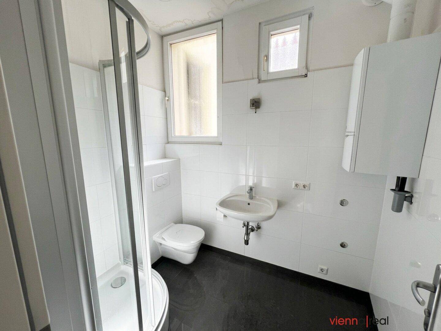 Modernisiertes Badezimmer mit Duschkabine, Toilette und Waschbecken, hell und funktional.
