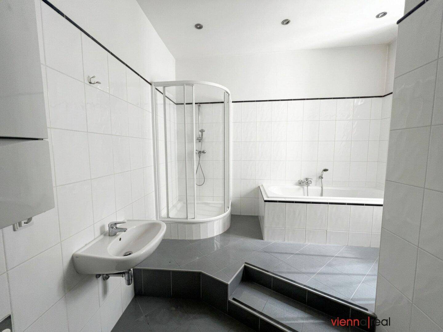 Gefliestes Badezimmer mit Badewanne, Duschkabine und Waschbecken, in gutem Zustand.
