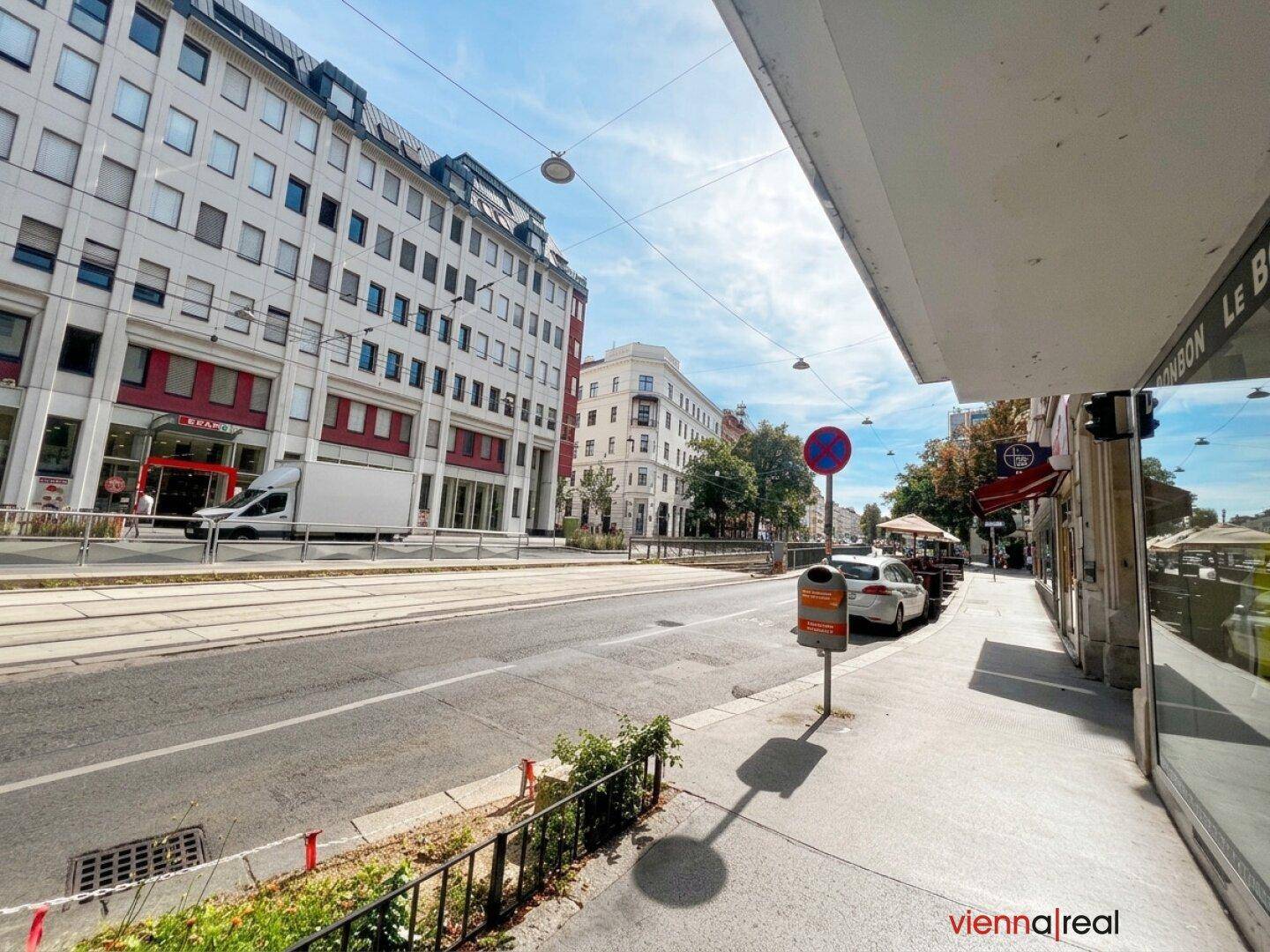 Straßenansicht mit Gebäuden, Straßenbahnlinien und einem sonnigen Himmel über der Stadt.