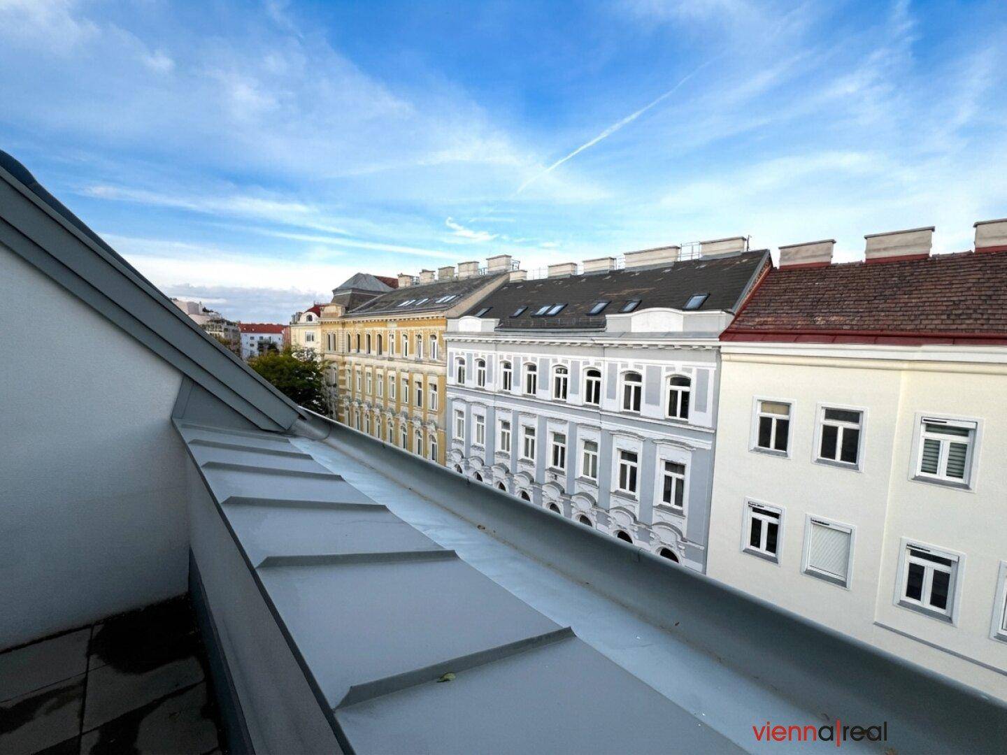 Blick vom Balkon auf eine Reihe von Altbauten mit traditionellen Dächern und Fassaden.