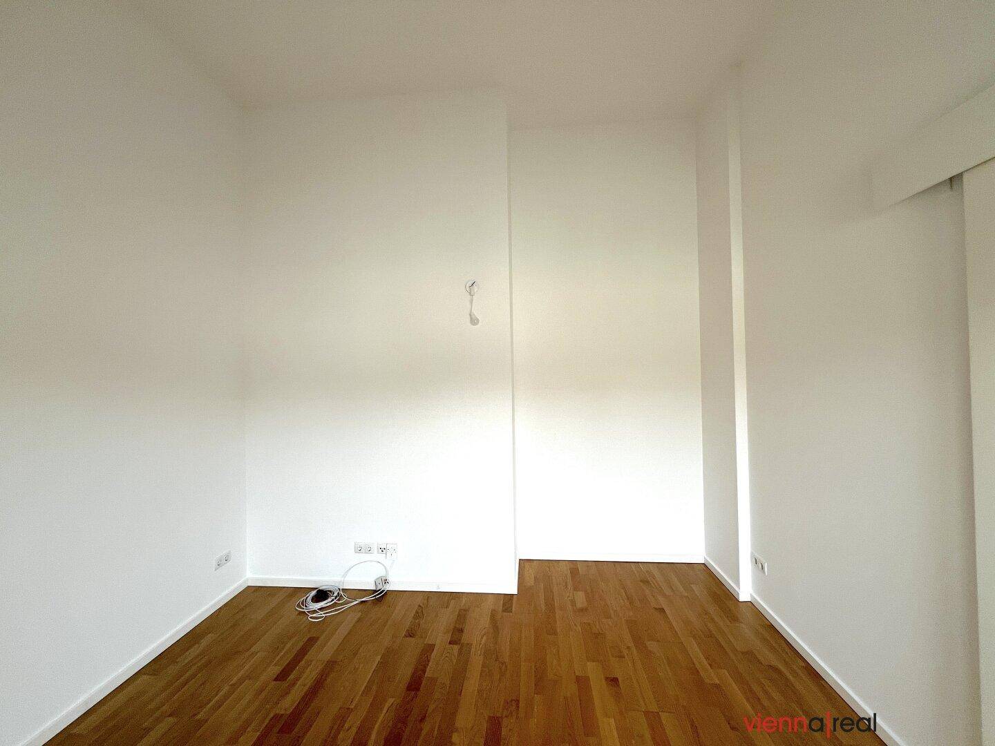 Leerer Raum mit Holzboden und weißen Wänden, bereit zur individuellen Gestaltung.