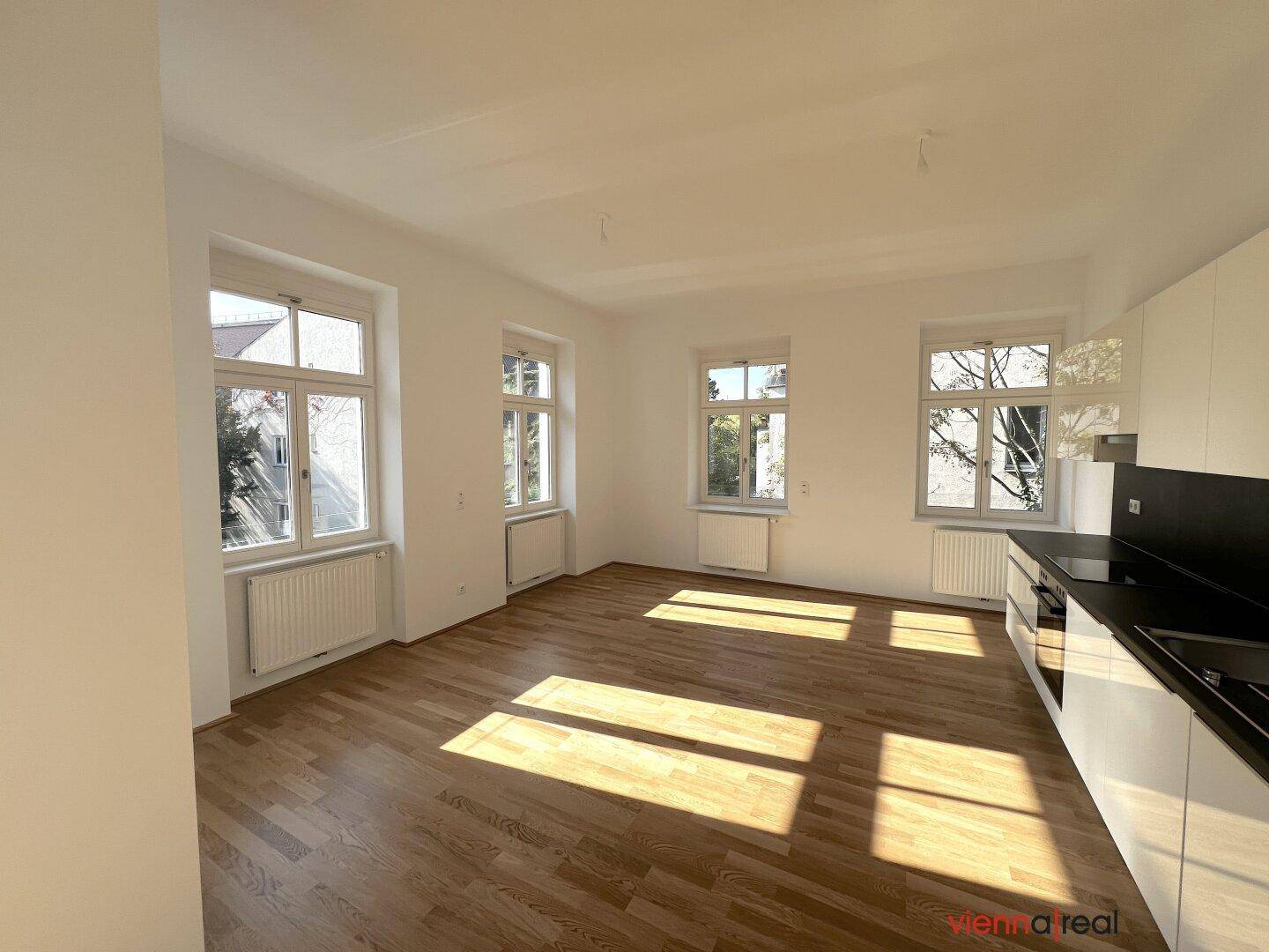Lichtdurchfluteter Küchenbereich mit Parkettboden und einer modernen, weißen Küchenzeile.