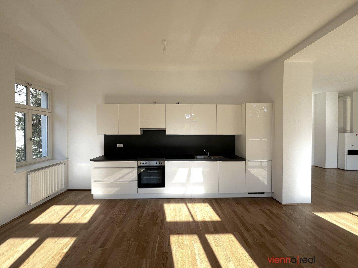 Moderne, weiße Einbauküche mit schwarzen Arbeitsplatten, integriertem Backofen und Dunstabzugshaube.