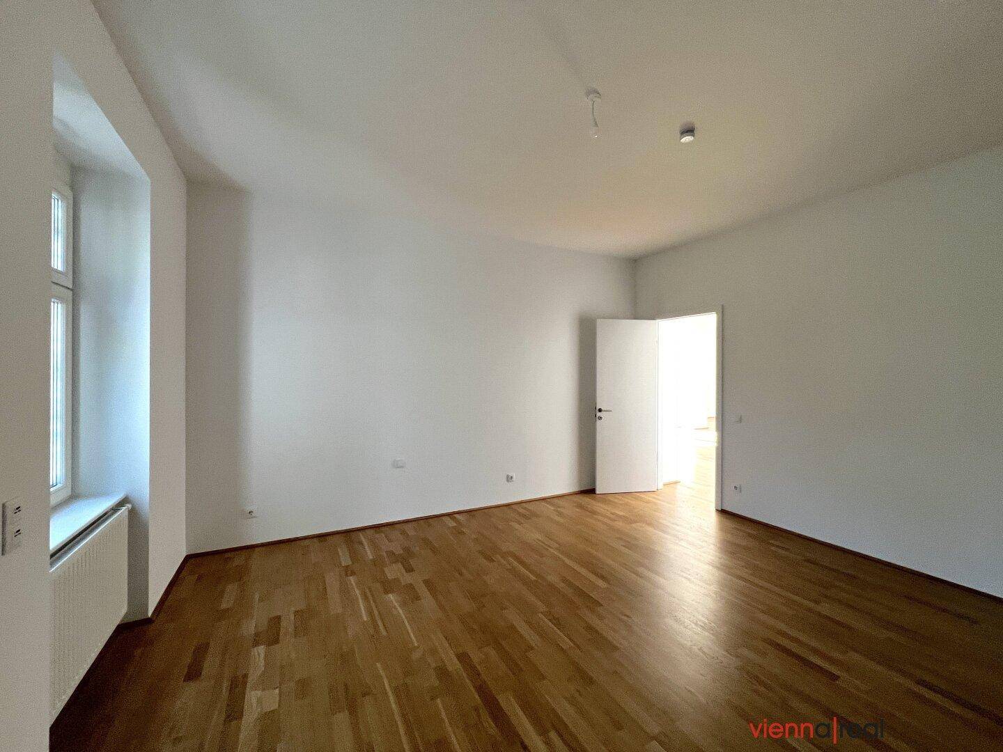 Helles Zimmer mit Parkettboden und weißen Wänden, bereit zur individuellen Gestaltung.