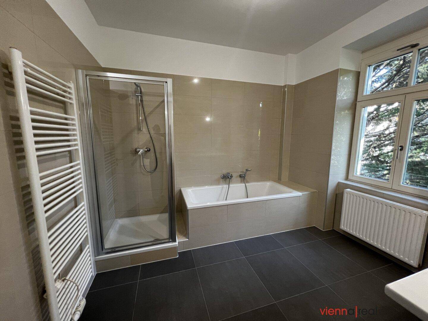 Modernes Badezimmer mit Badewanne, Duschkabine, beheiztem Handtuchhalter und Fenster.