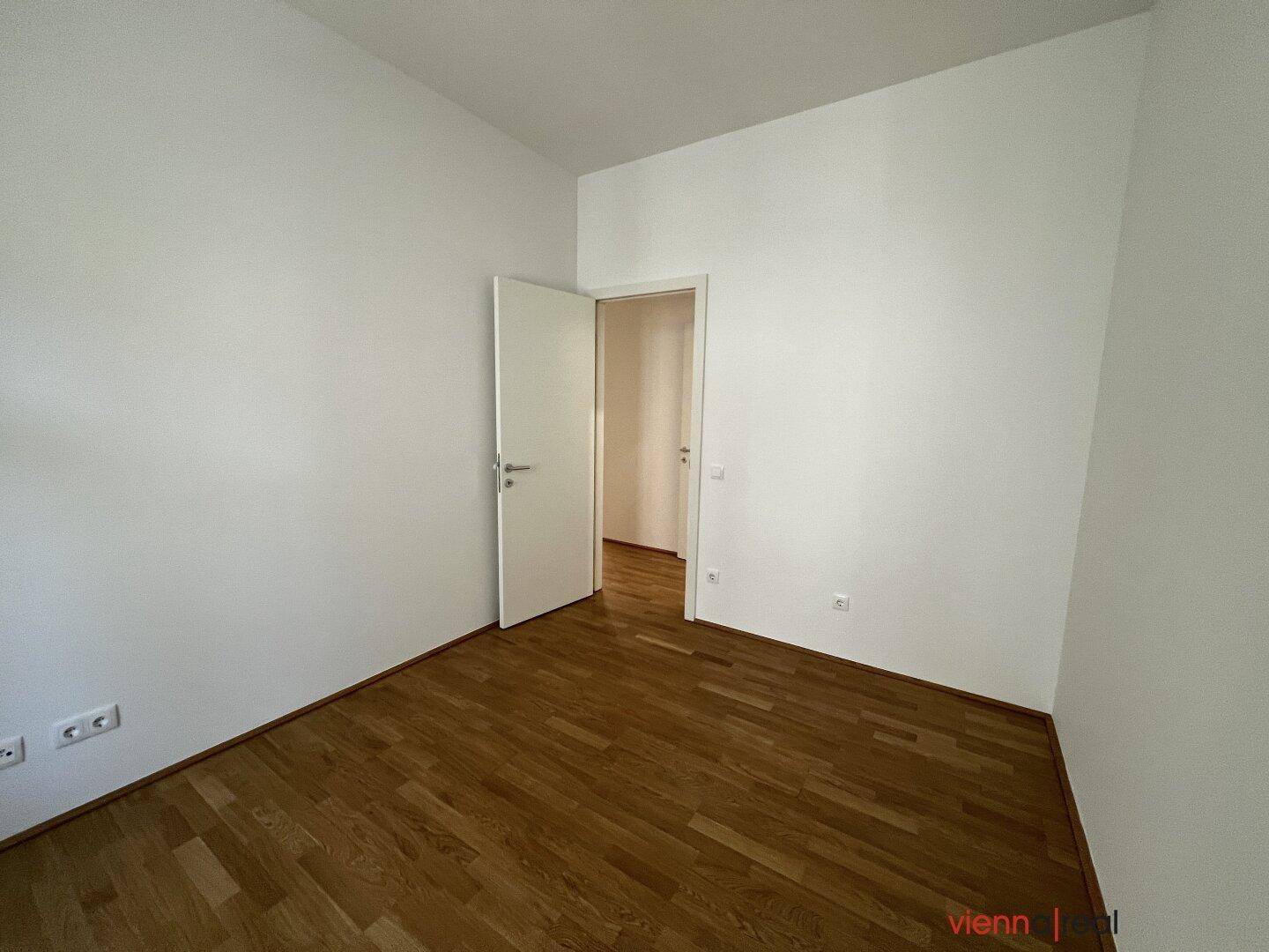 Leeres Zimmer mit Parkettboden und weiß gestrichenen Wänden, bereit zur Einrichtung.