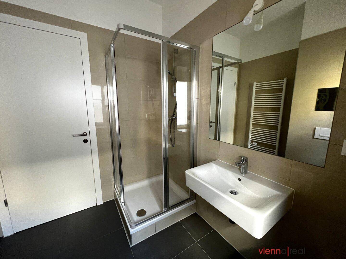 Funktionales Badezimmer mit Duschkabine, Waschbecken und großem Spiegel.