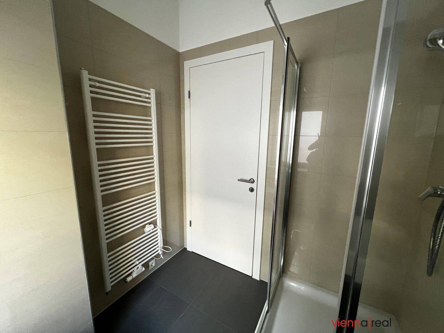 Badezimmer mit Duschkabine und beheiztem Handtuchhalter, praktisch und modern gestaltet.