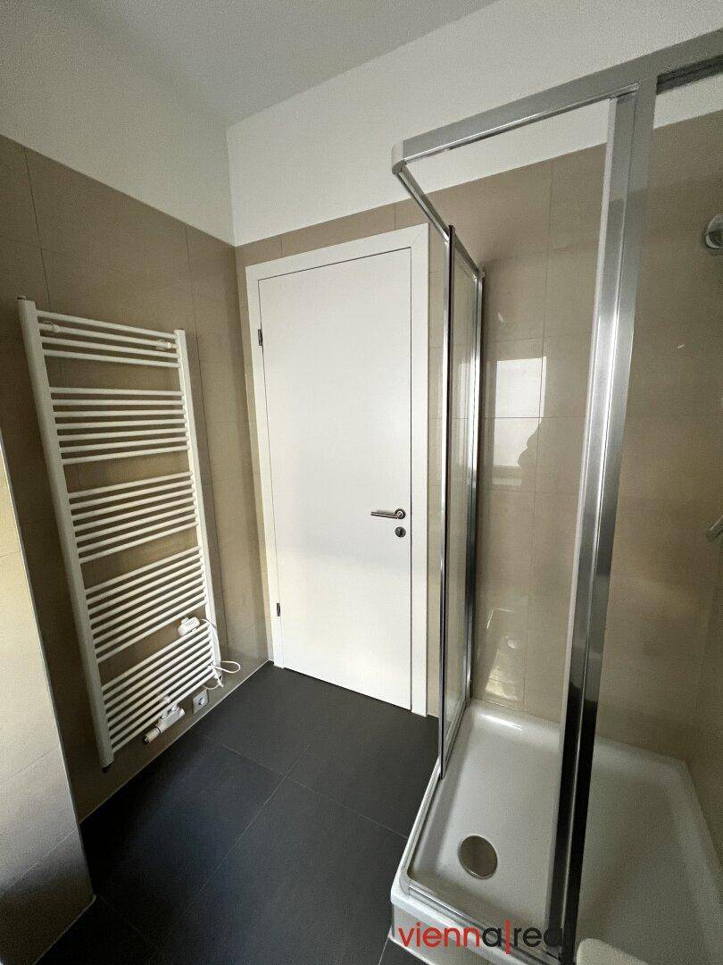 Helles Badezimmer mit Duschkabine und beheiztem Handtuchhalter, bietet Komfort.
